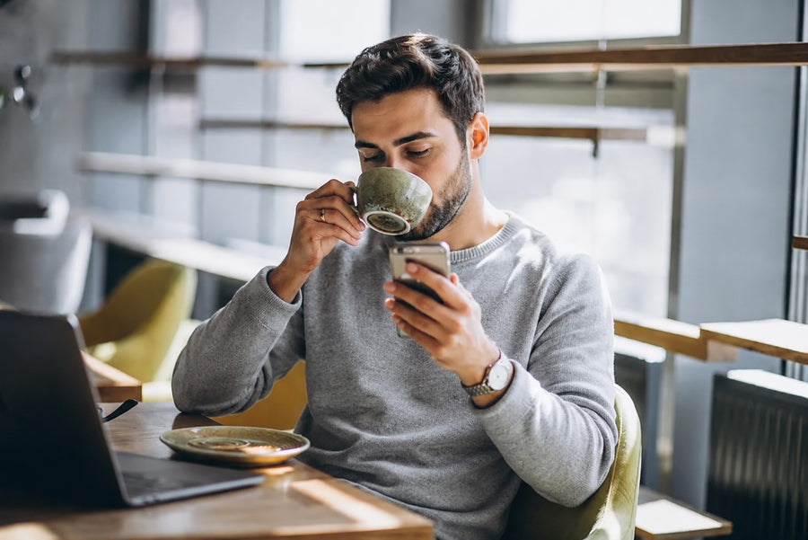Man drinking coffee while working at his laptop