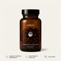 An amber glass supplement bottle with a black cap, labeled 'rubric' and 'Caffeine Recovery & Sleep Support', shown on a light warm-gray background with three feature badges below.