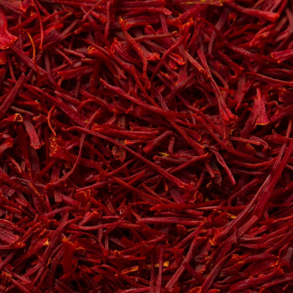 A close-up texture shot of dried red saffron threads filling the entire frame.